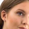 orhangen_titan_blomdahl_15-12146-01_7330981520611.jpg Close-up of a woman wearing elegant silver stud earrings adorned with diamonds, showcasing a sophisticated jewelry design.