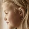 orhangen_titan_blomdahl_7330981158531_15-1255-12.jpg A young girl with blonde hair wearing heart-shaped earrings and a braided headband, showcasing a side profile view.