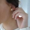 orhangen_titan_blomdahl_7330981520109_15-1268-01.jpg Close-up of a woman wearing elegant silver stud earrings with a sparkling design, showcasing a classic jewelry style.