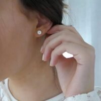 orhangen_titan_blomdahl_7330981520109_15-1268-01.jpg Close-up of a woman wearing elegant silver stud earrings with a sparkling design, showcasing a classic jewelry style.