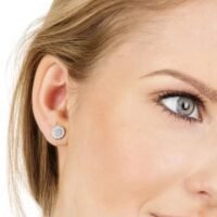 orhangen_titan_blomdahl_7330981560075_15-1491-01_b.jpg صورة مقربة لامرأة ترتدي أقراطًا فضية أنيقة تتميز بأحجار كريمة لامعة، مما يسلط الضوء على تصميم المجوهرات الحديث.