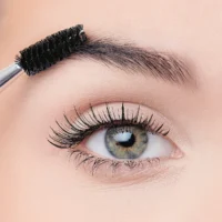9040 Close-up of a woman's eye with long eyelashes and an eyebrow brush grooming the brows, showcasing beauty and makeup application.
