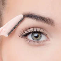 9042 Close-up of a person using a pink eyebrow razor for grooming eyebrows and facial hair, highlighting precision and detail.