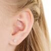orhangen_nickelfri_plast_blomdahl_7330981150207_15-0114-41_a.jpg Close-up of a woman's ear showcasing elegant diamond flower stud earrings, perfect for adding a touch of sparkle to any outfit.