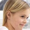 orhangen_nickelfri_plast_blomdahl_7330981512722_15-0114-98.jpg Close-up of a young girl with blonde hair wearing flower stud earrings, showcasing a delicate and stylish accessory for children.