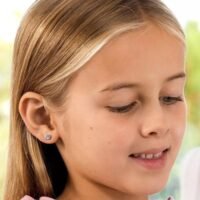 orhangen_titan_blomdahl_7330981156186_15-1424-06.jpg A young girl with long hair wearing small stud earrings, showcasing a joyful expression and natural beauty.