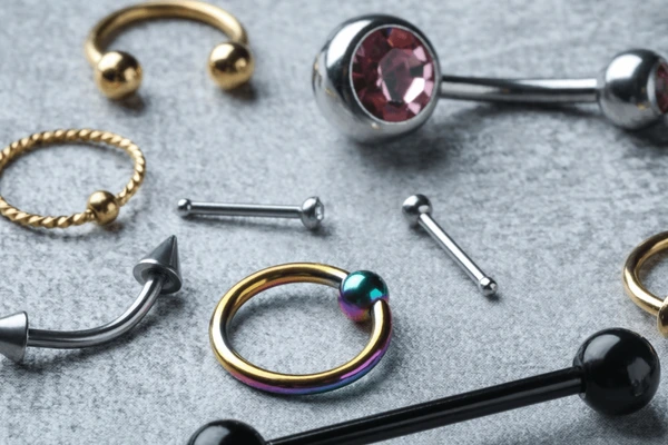 A collection of assorted body piercing jewelry including rings, studs, and barbells in various colors and styles.
